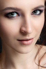 A gray-eyed girl with make-up and clean skin looks ahead close-up