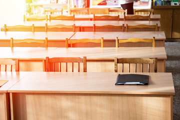 Empty tables in the classroom. On the table is a folder