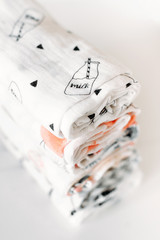 Pile of different cotton muslin or bamboo baby newborn blankets on white background. Set of infant blankets. Soft focus, vertical photo.