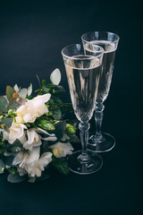 Two glasses of champagne and bouquet of white flowers