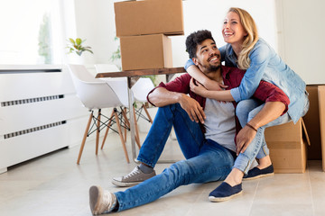 Young couple unpacking cardboard boxes at new home moving in concept