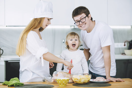 Family together happy young beautiful with a small child preparing dinner in the kitchen at home