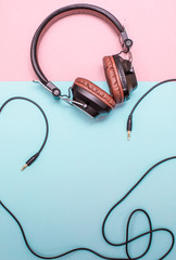 Fancy headphones laying on a flat pink and blue surface. Analog wire frames the layout.