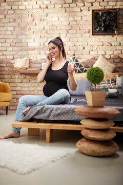 Happy pregnant woman sitting at home