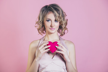 Beautiful woman model blonde woman with a heart and the make-up fashion on a pink background