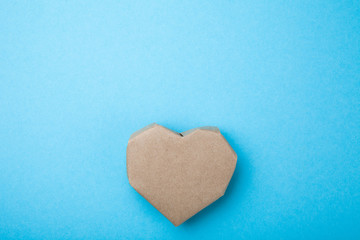 Homemade heart made from recycled paper on a blue background, empty space for text.