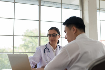 Women doctors are summarized the diagnosis results, patient men listening using laptop in the description.