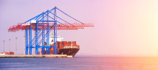 Container ship in the port on the horizon. Port crane loads a container on a ship. Cargo...