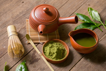 Matcha Green Tea and Japanese tea set. Ceramic teapot and a steaming cup on wooden background