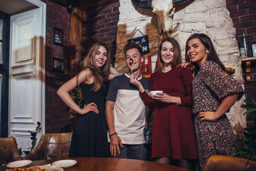 Four cool teenagers wearing casual clothes posing for camera in a stylish with hunting lodge interior design.