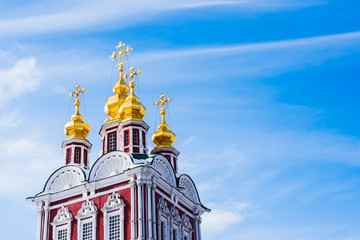 Fototapeta na wymiar Golden domes with crosses of old orthodox church on a background of beautiful blue sky