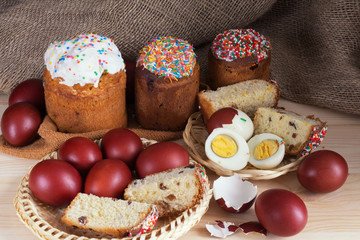 Easter cakes and painted eggs on a wooden table, in the background burlap.