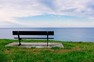 Naklejka na ściany i meble Empty wooden bench with a viewpoint looking out to sea