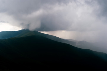 Storm rainy clouds above mountains. Apocalypse fantasy fabulous sky. Beautiful windy dramatic cloudscape at nature. Picturesque scenic view outdoor. Travel in wild territory. Discover rocky hills.