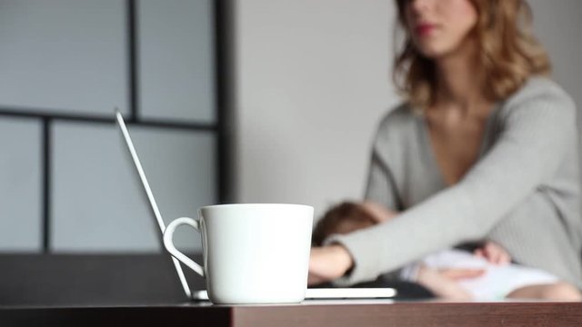 Mother with a child try to work on laptop computer at home