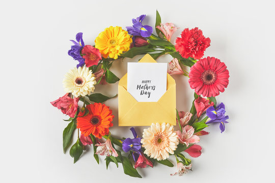 top view of beautiful floral wreath and happy mothers day greeting card in envelope on grey