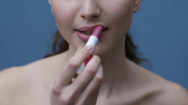 Young woman applying lipstick
