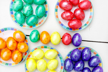 Easter eggs on wooden background. Colorful eggs in different colors - red, yellow, orange, purple and green.