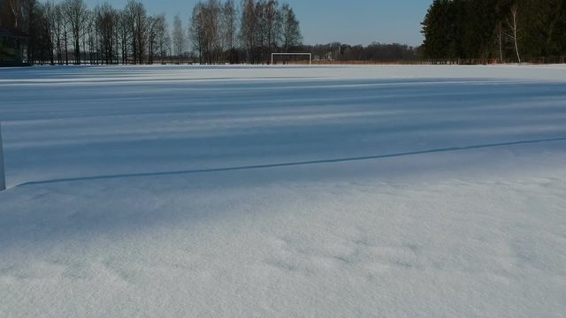 In small winter stadium drone flying through football gate on snowy field