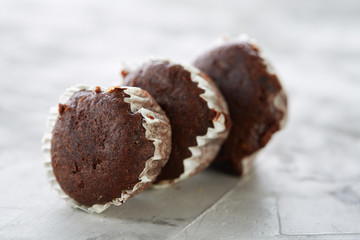 Tasty muffins arranged in pattern on light textured background, close-up, shallow depth of field, selective focus.