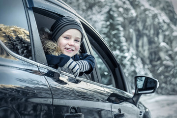 Happiness caucasian smilling boy looking out of black car window