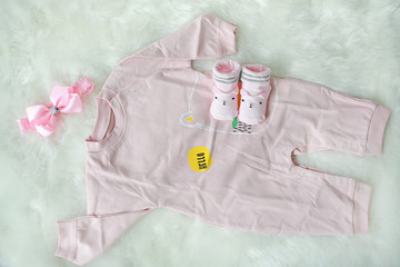 Collection items of bodysuits for newborn babies on white fur background shot from above.