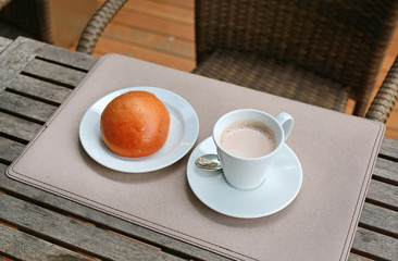 Hot chocolate drink in cup with buns on the table for breakfast.
