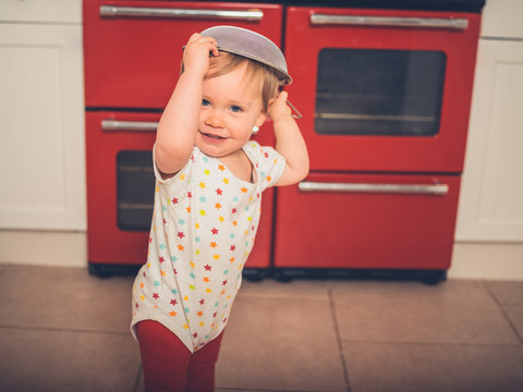 Little boy in the kitchen with collander on his head