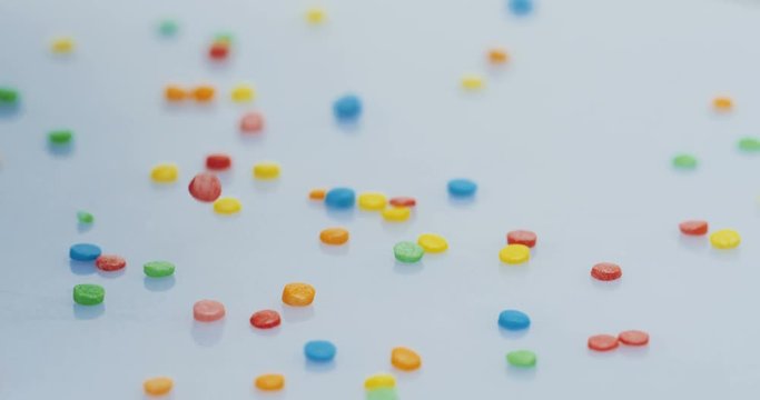 Macro shooting of the glazed little colourful candies falling down on the white background. Close up