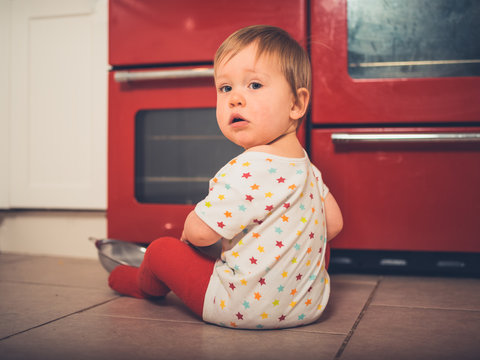 Little boy sitting by the stove in kitchen