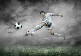 Obraz na płótnie Canvas Football player with ball in action under sky with clouds