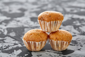 Tasty muffins arranged in pattern on light textured background, close-up, shallow depth of field, selective focus.