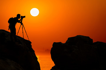 silhouette of photographer on top of mountain at sunset background