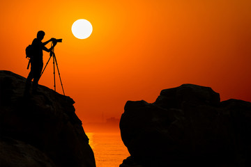 silhouette of photographer on top of mountain at sunset background