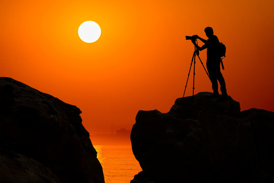 silhouette of photographer on top of mountain at sunset background - Powered by Adobe