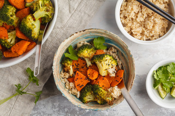 Brown rice with baked broccoli and sweet potato on white background, top view. Healthy vegan food concept.