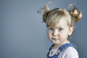  3 year old blond caucasian girl with pigtails with neutral and confident expression. straight look...