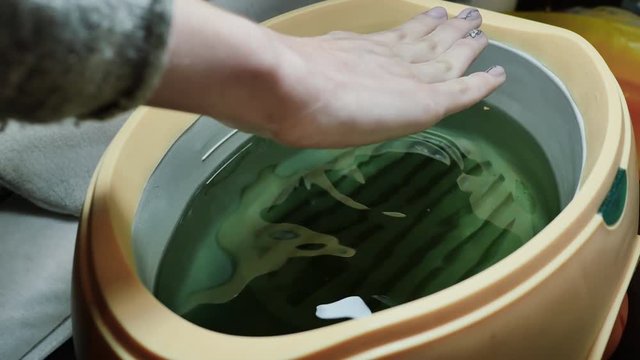 Process paraffin treatment of female hands in beauty salon.