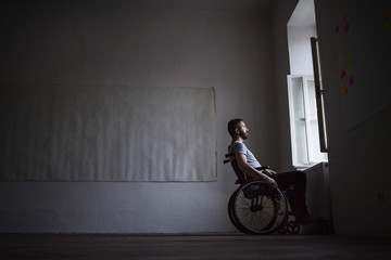 Man in wheelchair looking out of the window.
