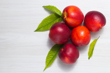 Peaches with leaves on a white wooden table Top view with space for text