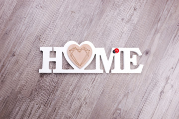 The word Home in white letters on dark wood background