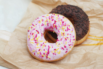 Two Glazed Donuts Lying on craft paper background. Sweet dessert for Breakfast.