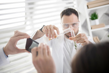Serious experiment. Attractive concentrated young experienced ecologist holding a test tube and...