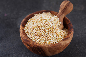 Seeds of white quinoa in wooden bowl copy space