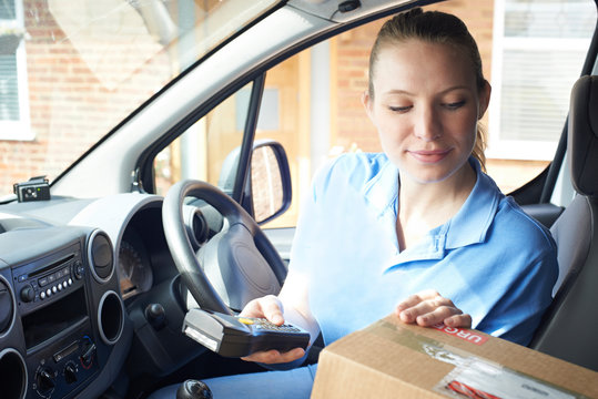 Female Courier In Van Delivering Package To Domestic House