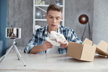 Being a blogger. Nice smart young well-built man talking and showing a dinosaur skull while making...