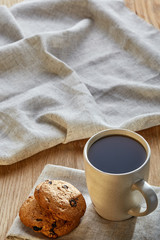 Porcelain teacup with chocolate chips cookies on cotton napkin on a rustic wooden background, top view