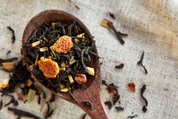 Closeup of a wooden spoon filled with scattered tea leaves, shallow depth of field, top view