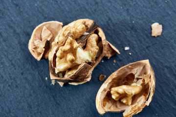 Top view close-up shot of cracked walnuts on dark background, shallow depth of field, macro