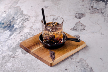 Close up, brown alcoholic cocktail with whiskey, ice cubes decorations on a wooden board, gray...